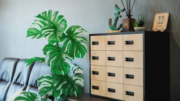 A room with a large potted plant, a cabinet with numbered drawers, and a sign indicating a bus terminal inn.