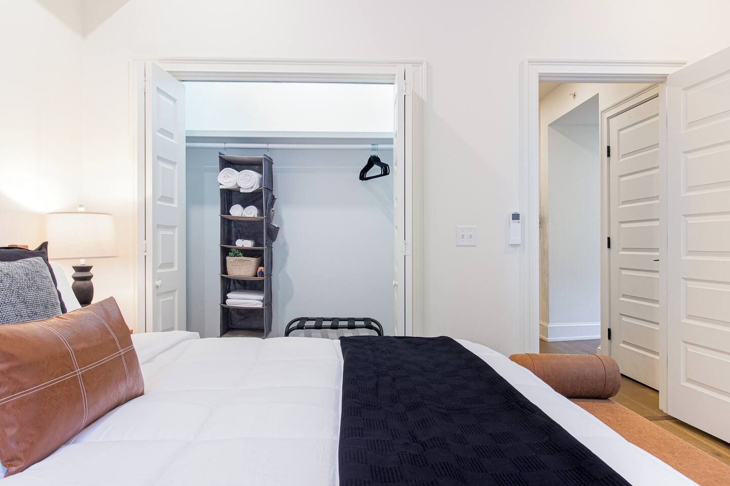 A bedroom with a bed, a bedside table, a lamp, a wardrobe, and a closet.