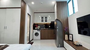 Ein modernes Schlafzimmer mit Bett, Einbauschrank und einer kleinen Küchenzeile mit Waschmaschine.