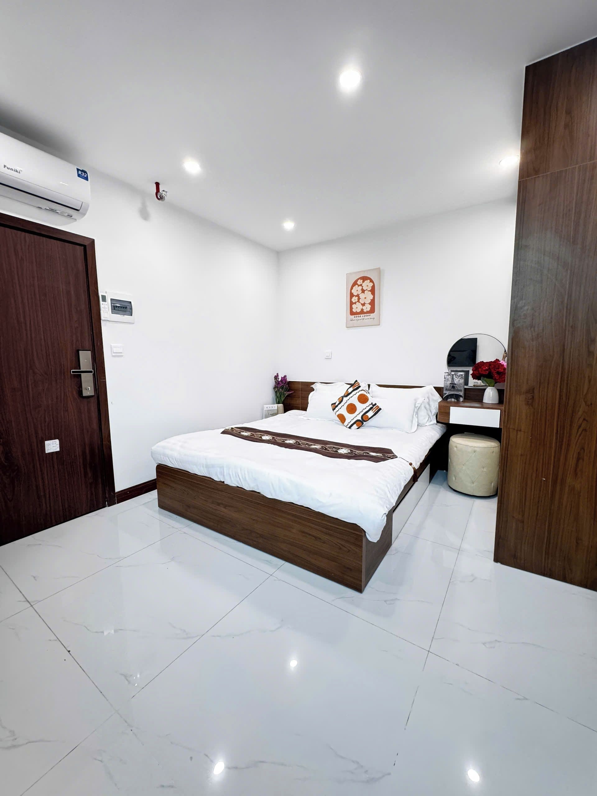 A modern bedroom with a wooden bed, white walls, a small bedside table, and a nightstand.
