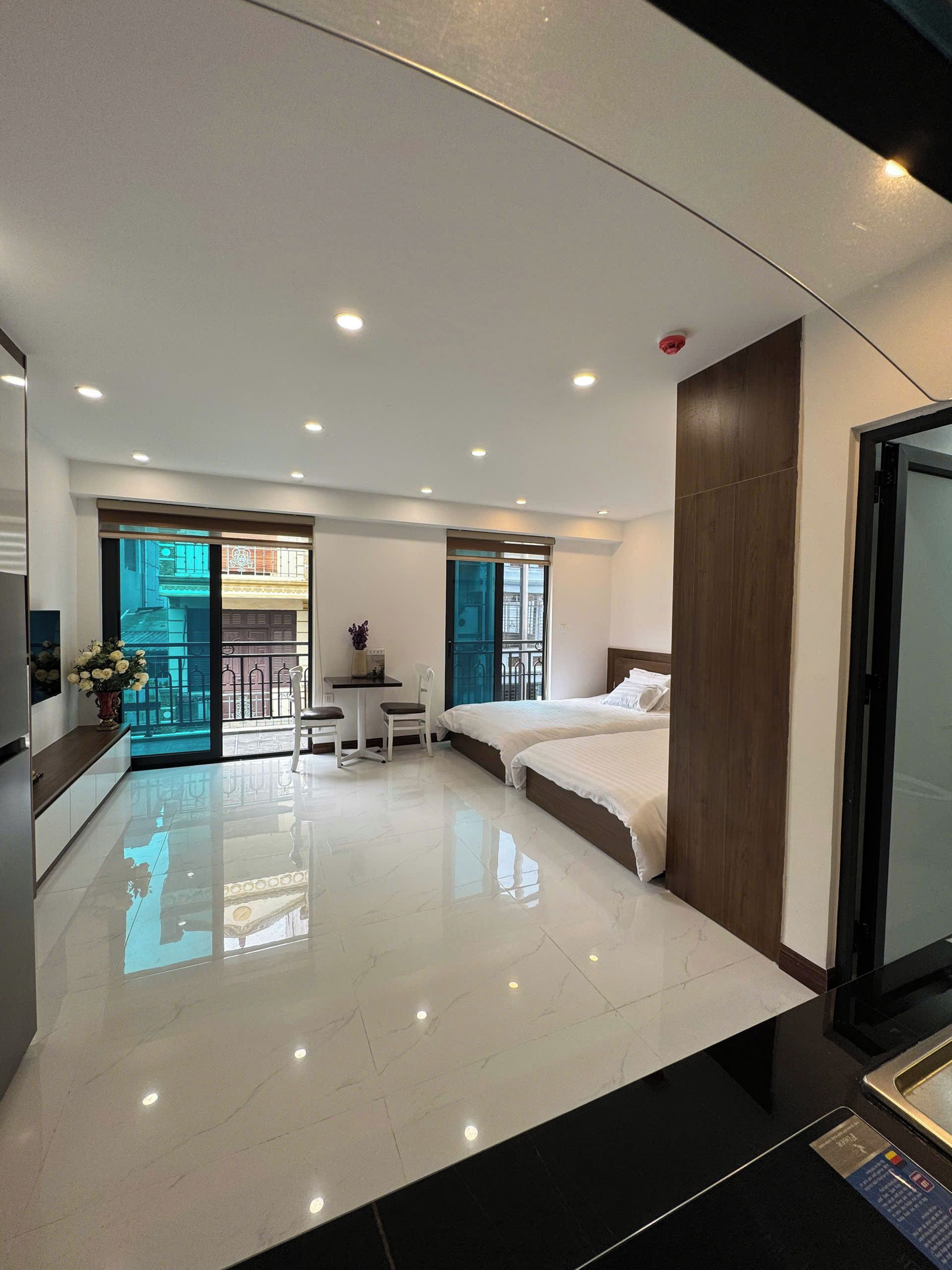 A modern hotel room with a large bed, a desk, and a balcony with a view.