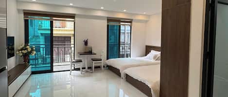 A modern hotel room with a large bed, a desk, and a balcony with a view.