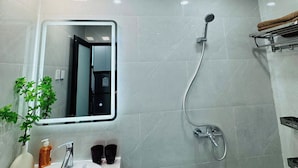 Ein Badezimmer mit einem weißen Waschbecken, einem Spiegel, einer Dusche und einem Handtuchhalter.