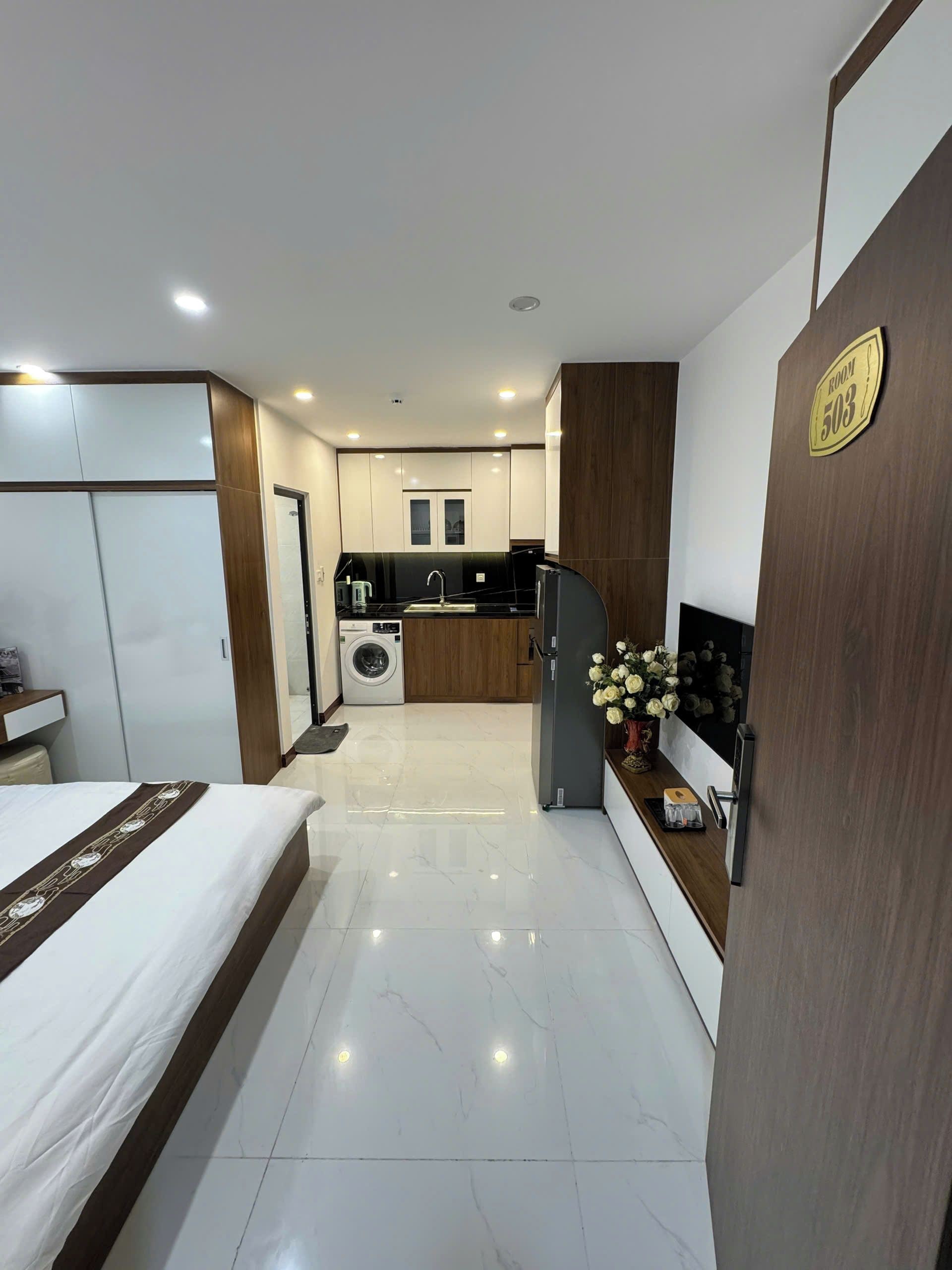 Een hotelkamer met een bed, een kleine kitchenette, een wasmachine en een badkamer.