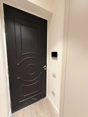 Uma porta preta fechada com olho de fechadura e campainha.