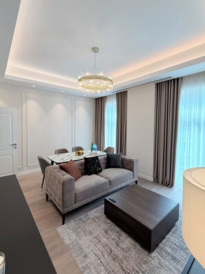 Ein modernes Wohnzimmer mit Sofa, Esstisch und einer Deckenleuchte.