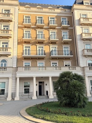Ein mehrstöckiges Gebäude mit einer symmetrischen Fassade, mehreren Balkonen und einem zentralen Eingang mit Säulen.