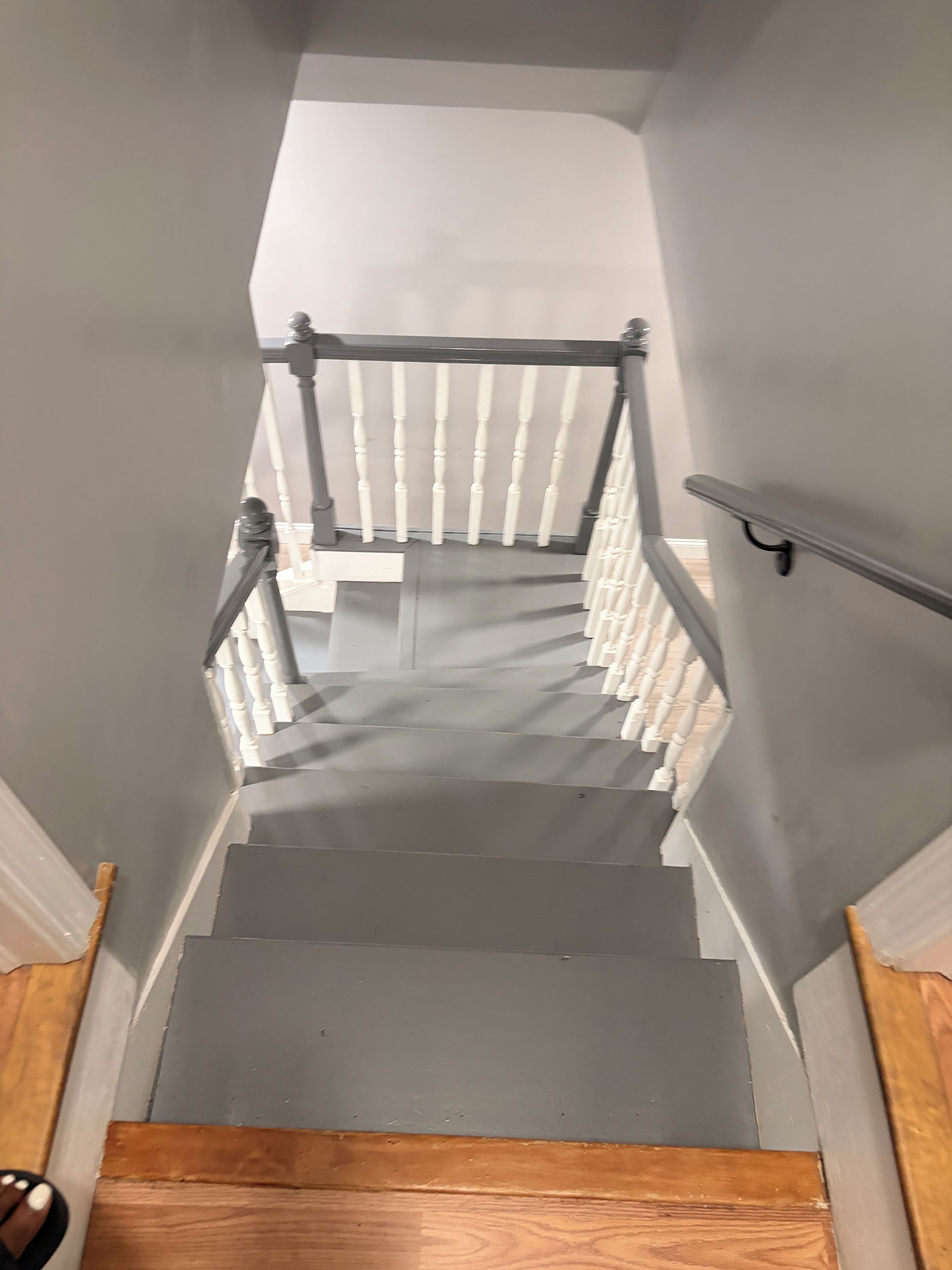 Eine Treppe mit weißen Balustern, einem Geländer auf der rechten Seite und einem Holzboden unten.