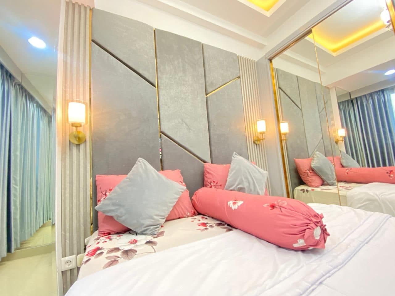 A modern bedroom with a large bed, a headboard with geometric patterns, and a full-length mirror.