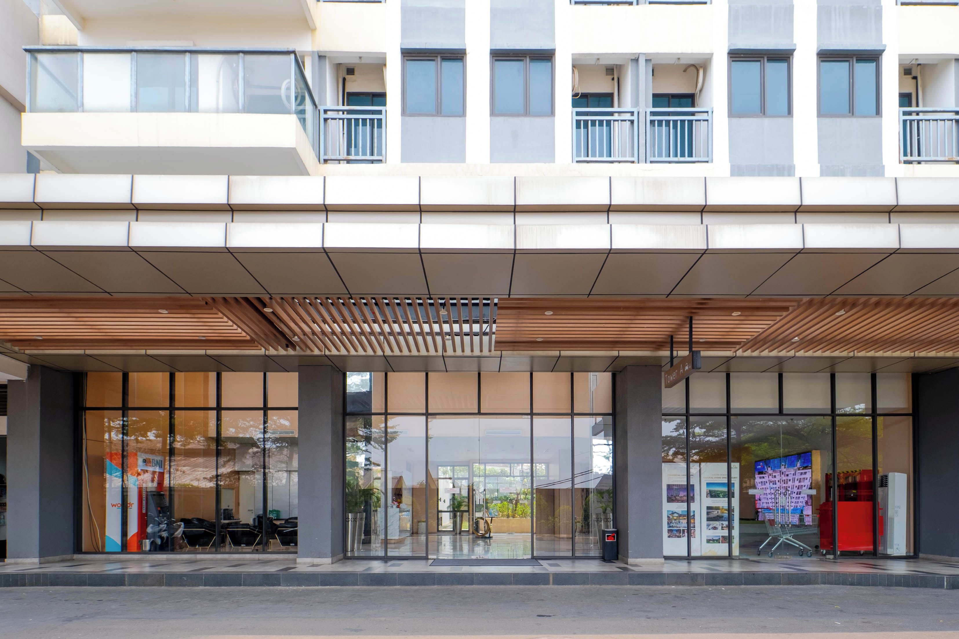 Un edificio moderno con entrada cubierta, amplias ventanas y un cartel que indica 'Tower A'.
