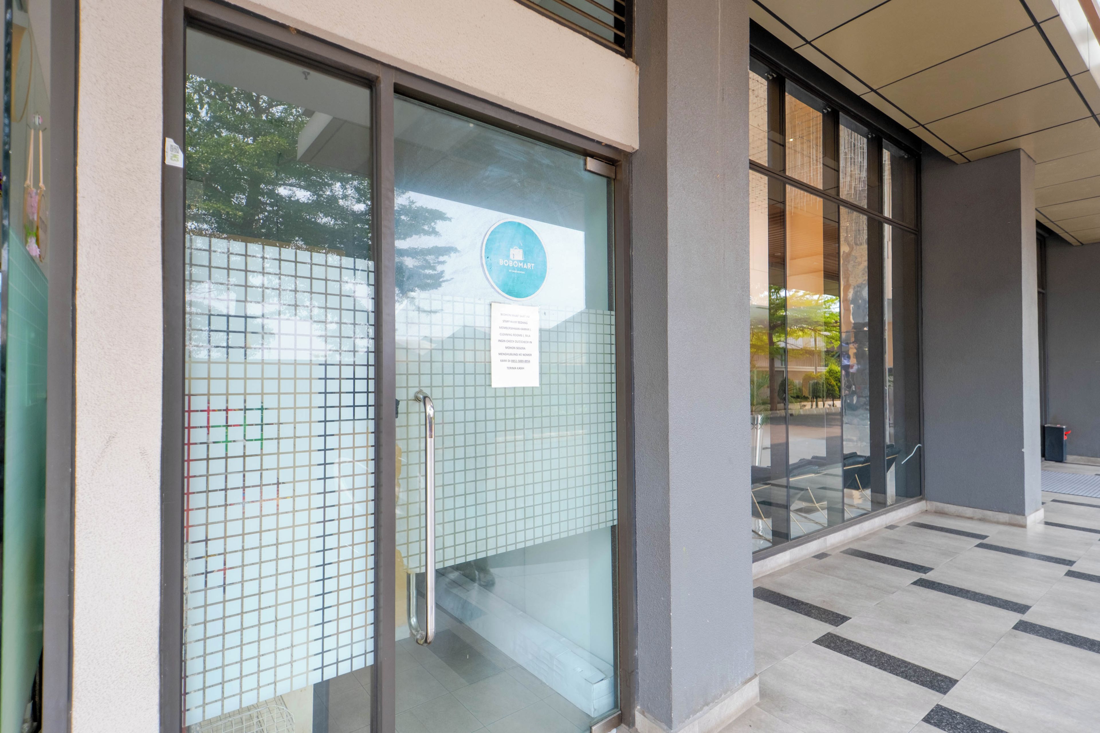 A hotel entrance with a glass door, a metal handle, and a sign indicating a cleaning room.