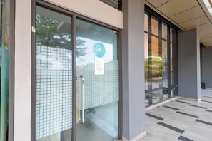 Ingresso di un hotel con porta in vetro, maniglia in metallo e cartello che indica una lavanderia.