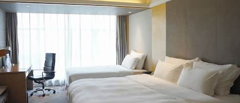 A hotel room with two beds, a desk, and a chair.