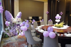 A dining area with a round table set for a meal, surrounded by chairs.