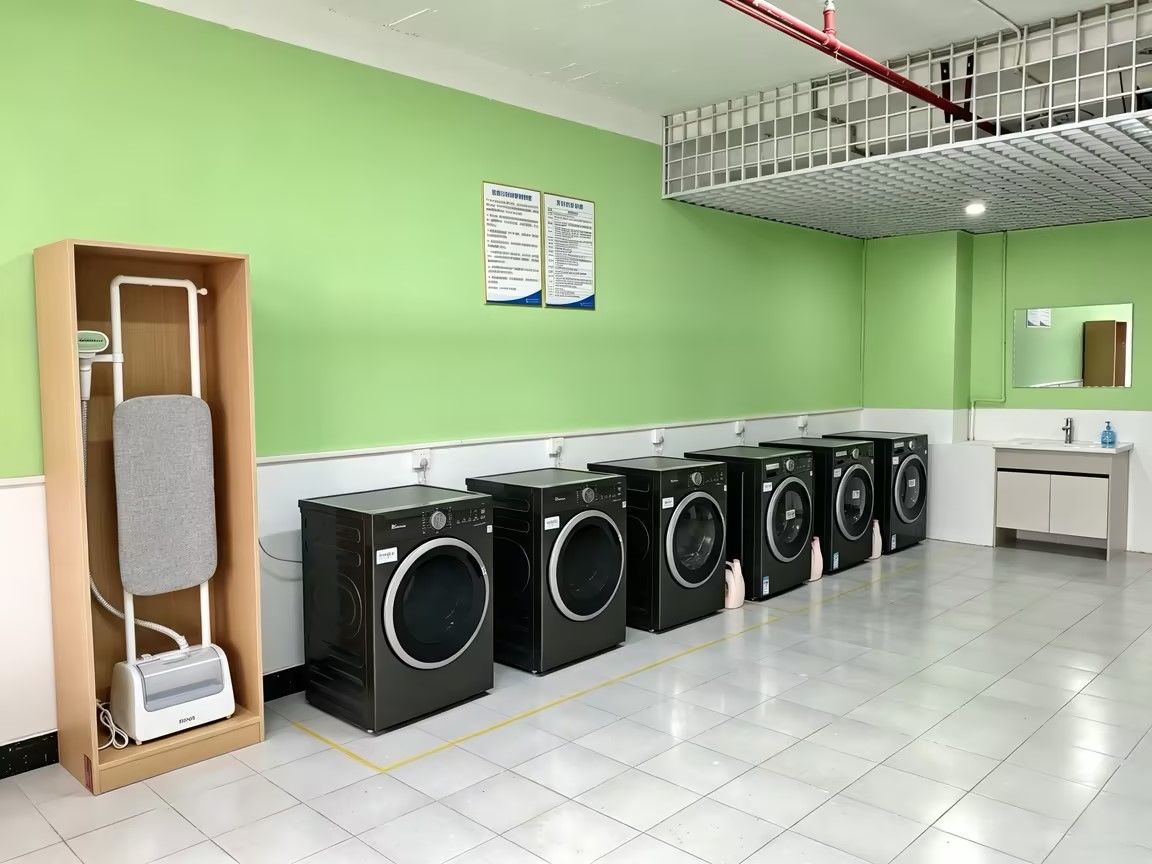 A laundry area with multiple washing machines, a drying rack, and a sink.