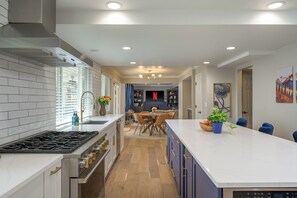 A modern kitchen with a central island, a dining area with a round table, and a living space with a fireplace.