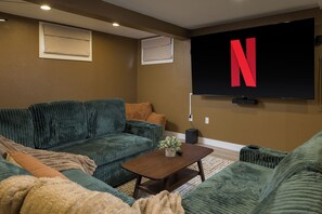 Una sala de estar con un sofá verde, una mesa de centro y un televisor de pantalla plana montado en la pared.