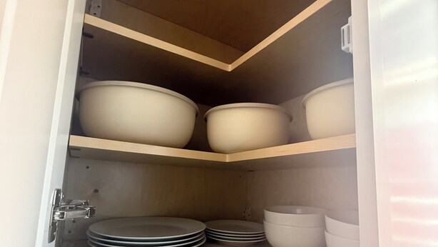 A kitchen cabinet with shelves holding bowls, plates, and a colander. - The Northridge Nook: A Cozy 1-bedroom house in Los Angeles with AC & Pool Access (Los Angeles)