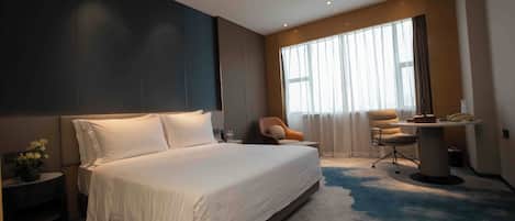 A modern hotel room with a large bed, a desk, and a chair.