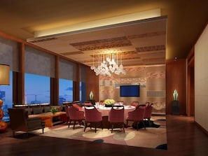A modern dining area with a chandelier, round table, and red chairs.