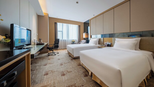 A hotel room with two beds, a desk, a television, and a large window. - Grand Skylight International Hotel Ganzhou (Ganzhou)
