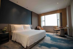A modern hotel room with a large bed, a desk, a chair, and a window with curtains. - Grand Skylight International Hotel Ganzhou (Ganzhou)