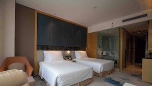 A hotel room with two beds, a sofa, a desk, and a glass-enclosed shower area. - Grand Skylight International Hotel Ganzhou (Ganzhou)