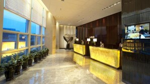 A hotel lobby with a reception desk, potted plants, and a large window. - Grand Skylight International Hotel Ganzhou (Ganzhou)