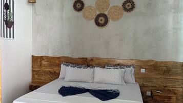 A room with a bed, a ceiling fan, a wall-mounted light fixture, and a decorative wall piece.