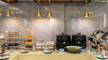 A buffet setup with various food items and serving utensils.