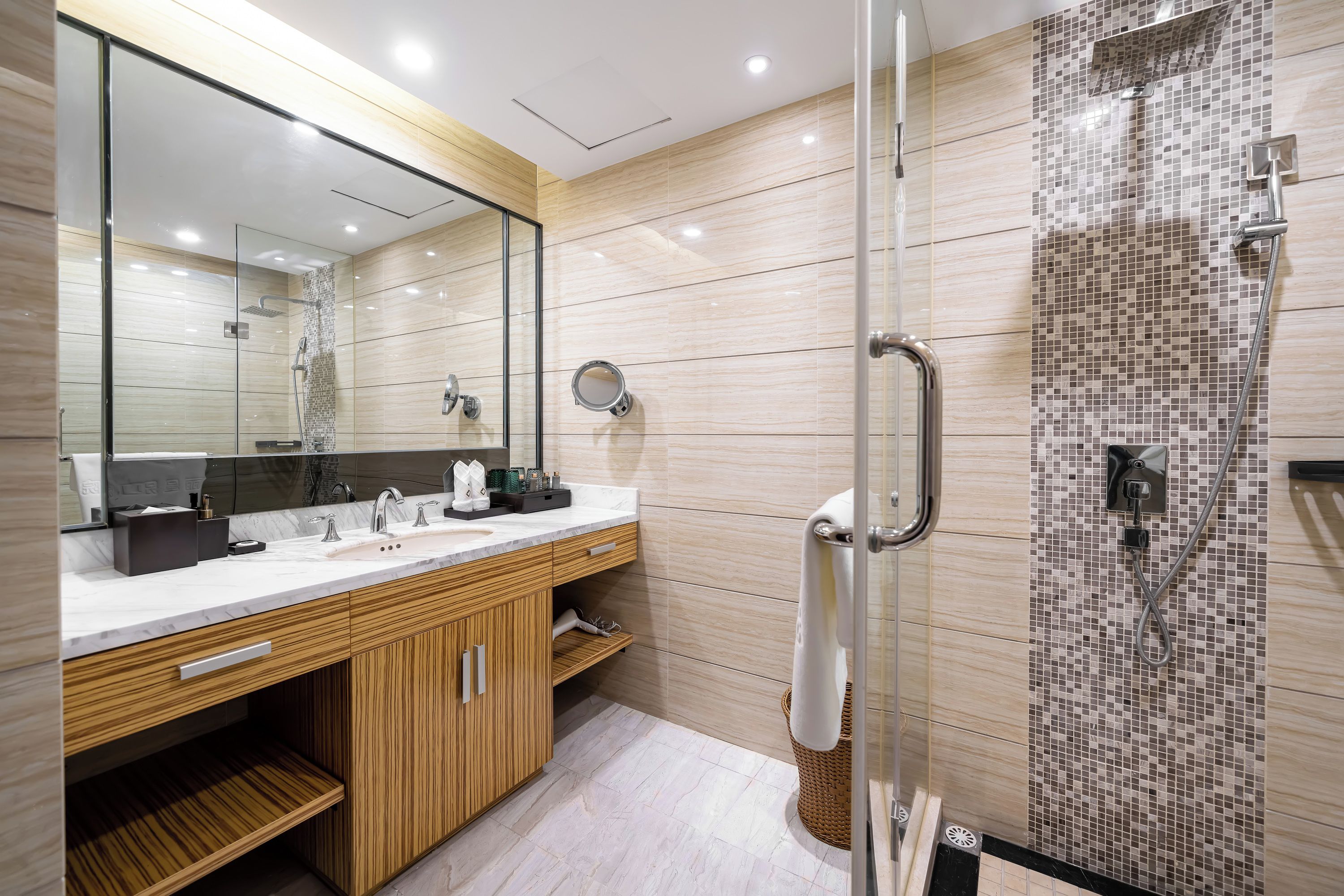 A modern bathroom with a glass shower enclosure, a vanity with a mirror, and a tiled shower wall.
