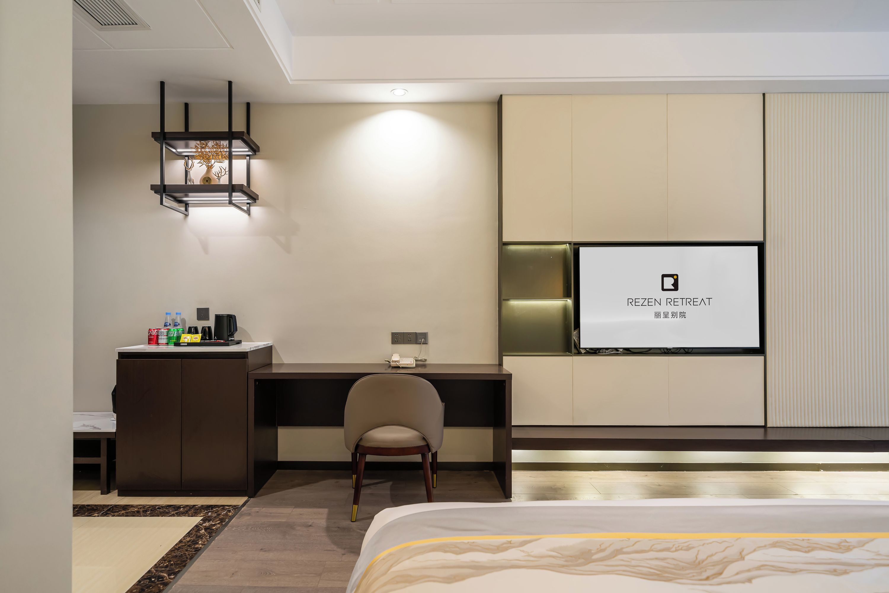A hotel room with a bed, a desk, a chair, a TV, and a minibar.