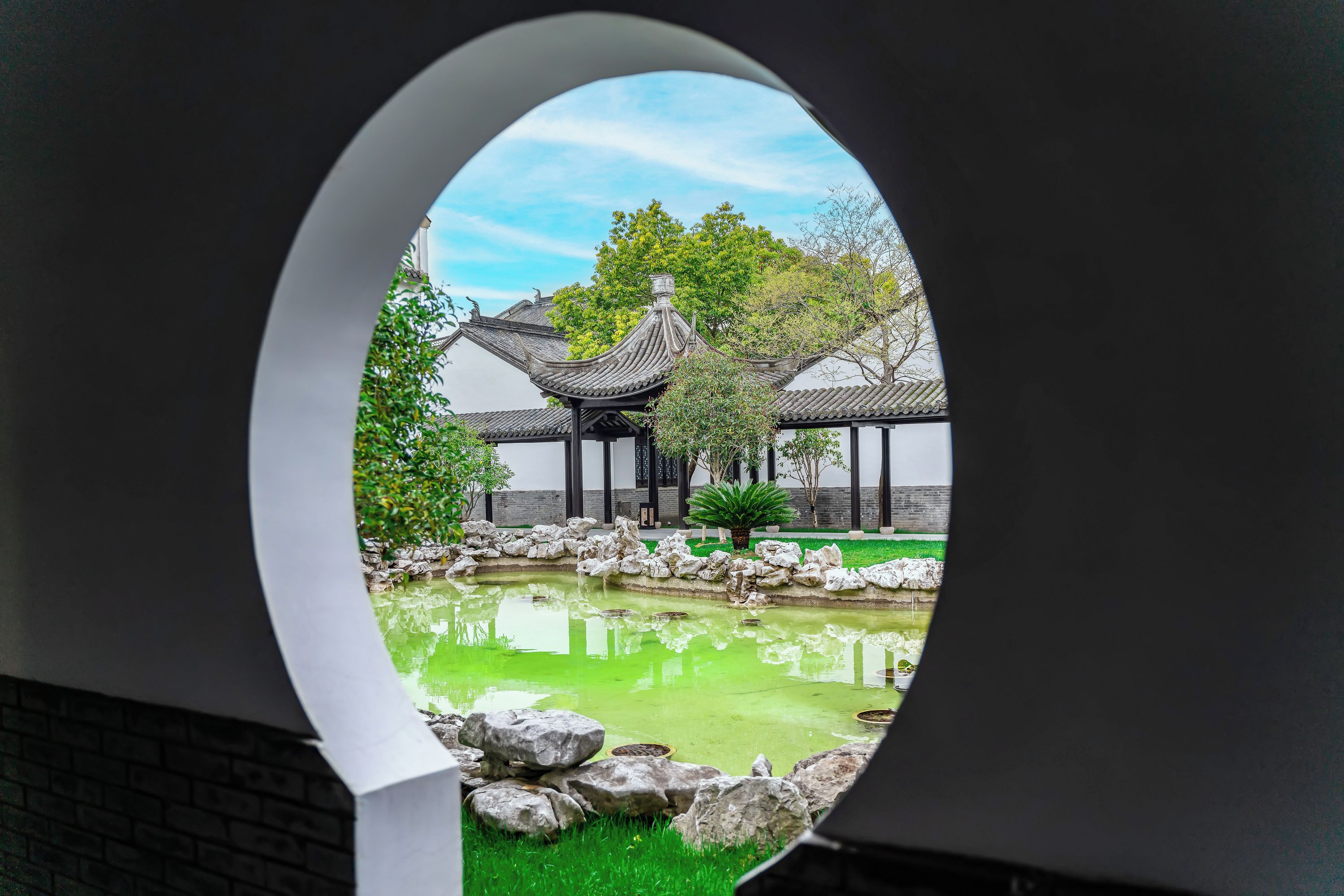 A traditional Chinese pavilion with a pond and rocks.
