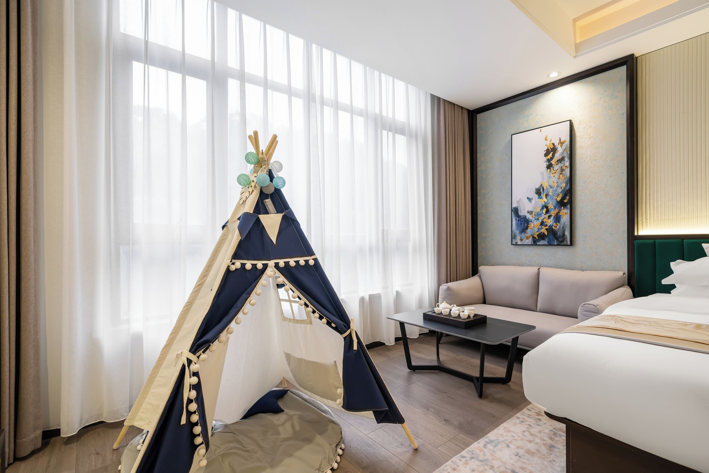 A hotel room with a bed, a sofa, a small table, and a decorative teepee.