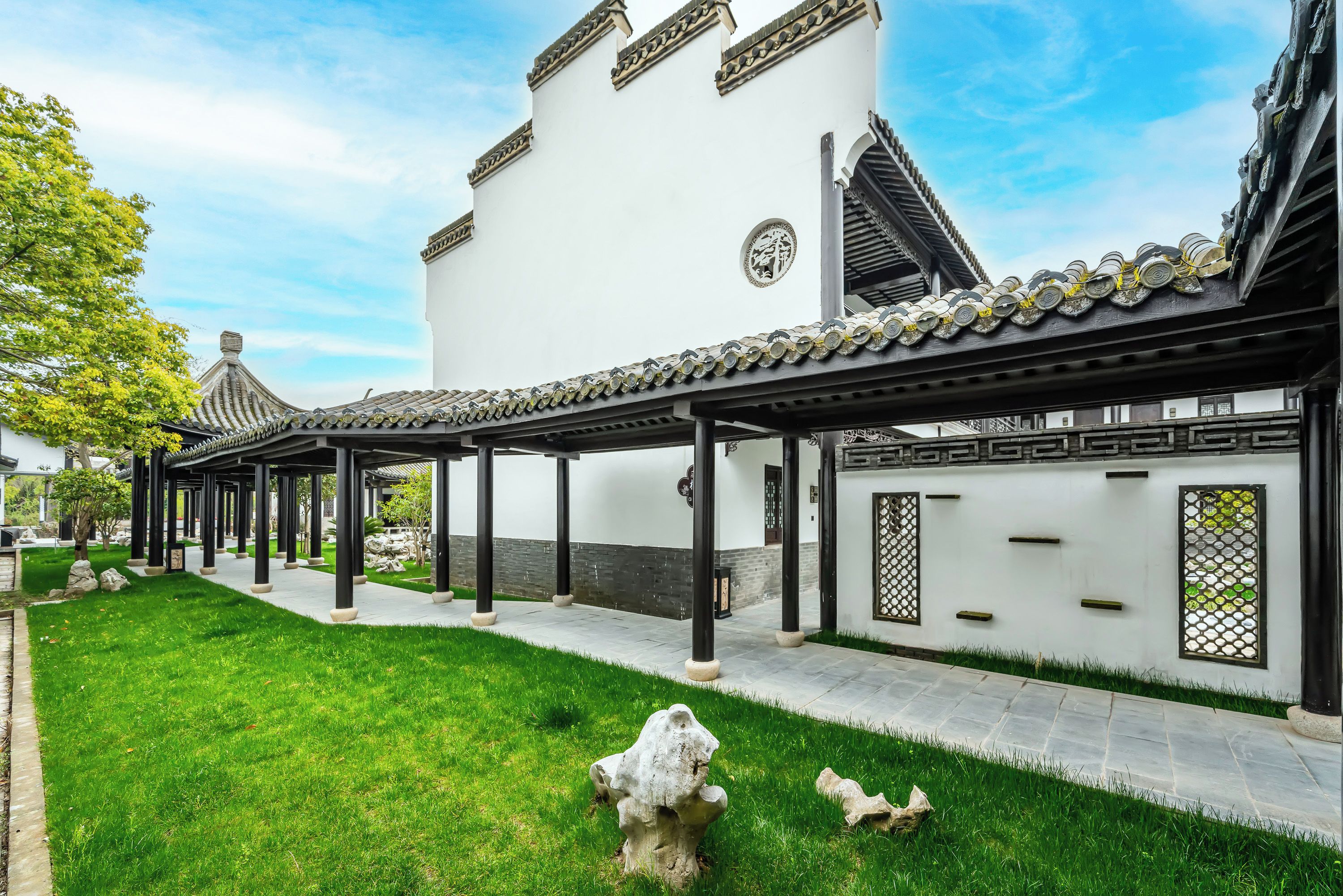 A traditional building with a tiled roof, a covered walkway, and a well-maintained lawn.