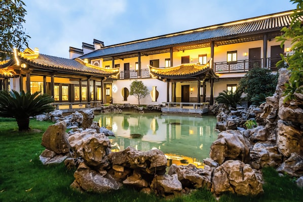A traditional building with a courtyard, a pond, and a well-maintained garden.