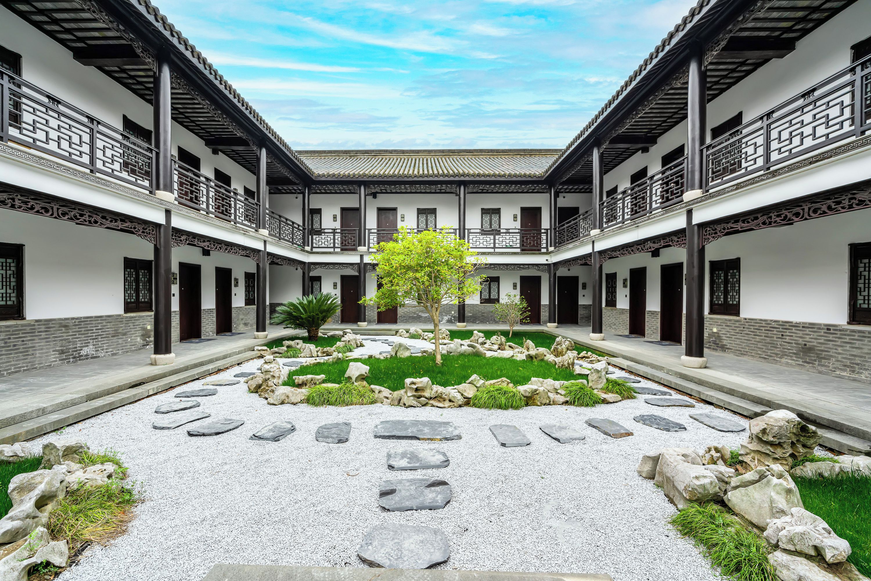Um pátio central com jardim, rodeado por edifícios tradicionais com vários andares e varandas.