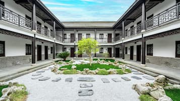 Um pátio central com jardim, rodeado por edifícios tradicionais com vários andares e varandas.