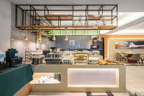 Un buffet proposant une variété de plats, un coin café et des espaces aménagés pour s’asseoir.