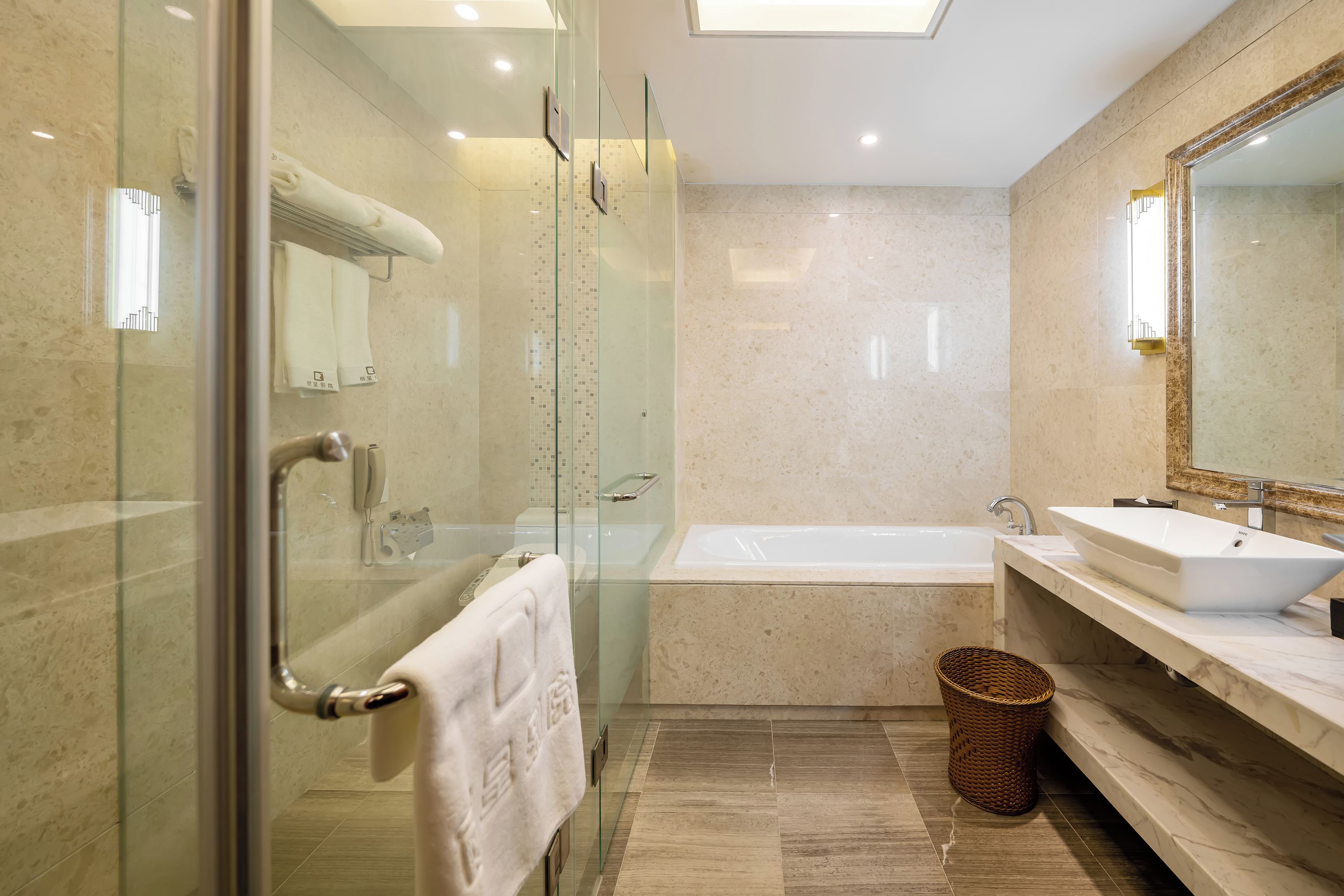 A modern bathroom with a glass-enclosed shower, a standalone bathtub, and a vanity with a large mirror.
