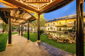 A courtyard with a traditional building, a stone pathway, and a small pond.