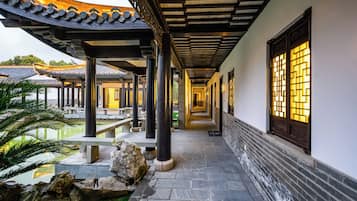 A corridor with traditional architecture, stone flooring, and a water feature.