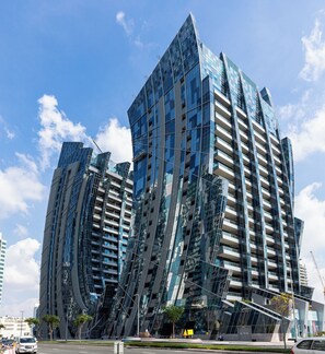 A modern high-rise building with a unique angular design, featuring multiple balconies and large windows. - Designer Duplex PrivatePool, Large Patio (Dubai)