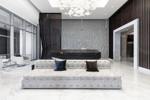 A modern lobby with a tufted sofa, a reception desk, and a decorative wall. - Designer Duplex PrivatePool, Large Patio (Dubai)