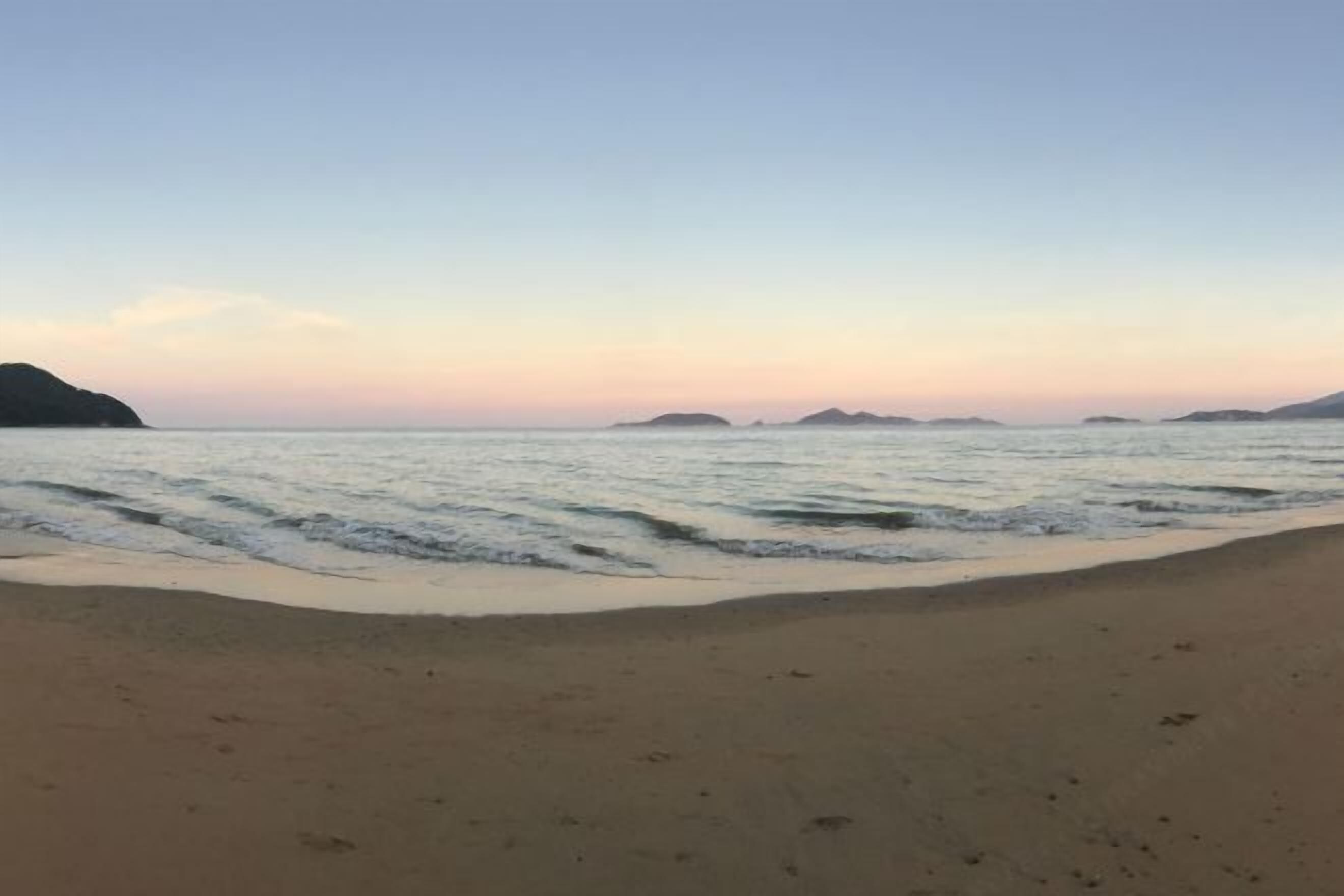 A beach with a sandy shore and calm water.