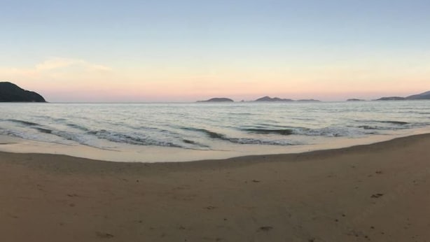 Uma praia com areal arenoso e águas calmas.