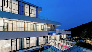 Um edifício moderno de dois andares com piscina e área de estar ao ar livre.