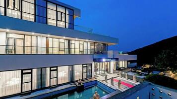 A modern two-story building with a swimming pool and outdoor seating area.