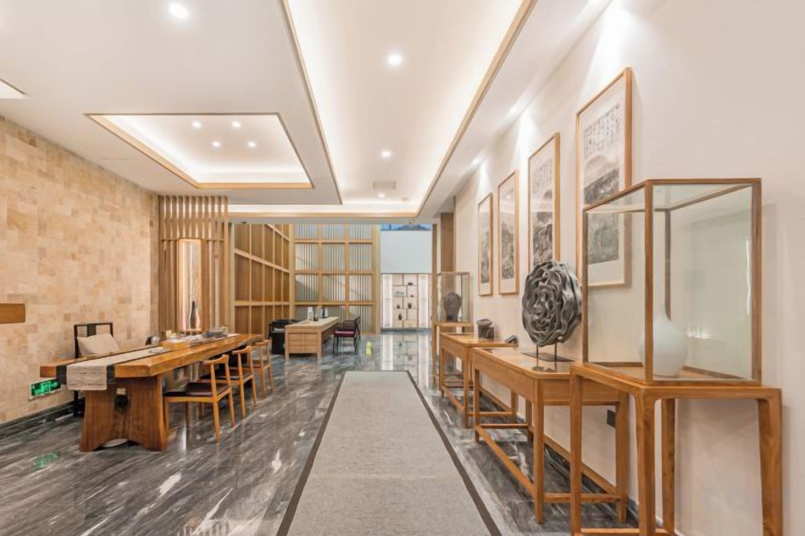 A modern interior with a long hallway, wooden furniture, and framed artwork.
