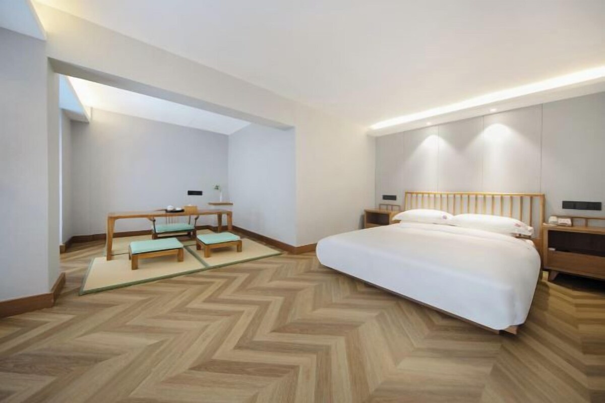 Un hotel modern amb un llit gran, una taula de treball i vista al cel.